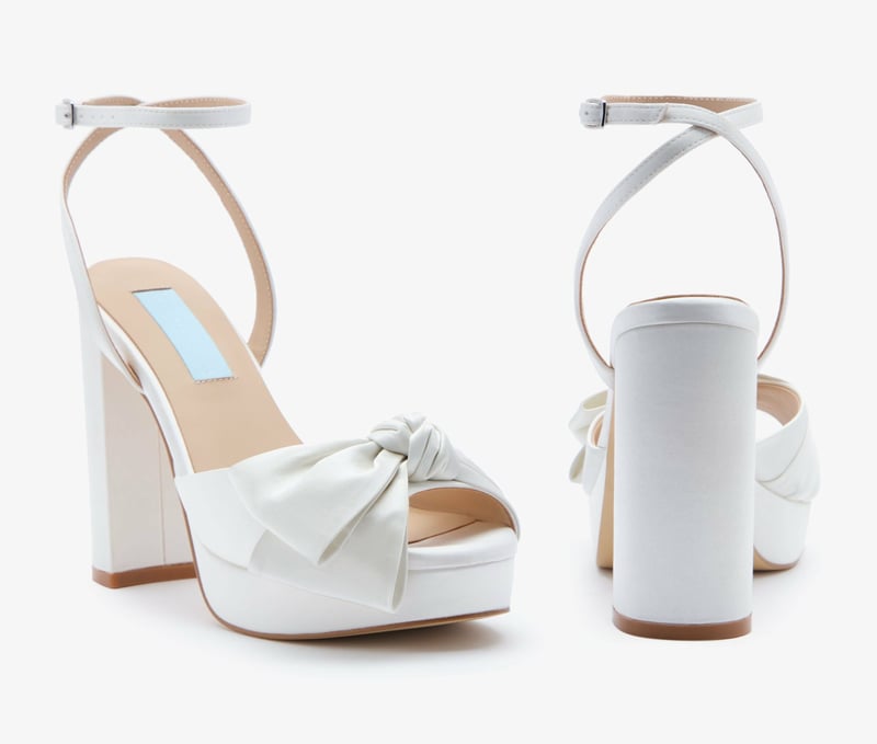 a pair of ivory satin platform heels with bow detail.