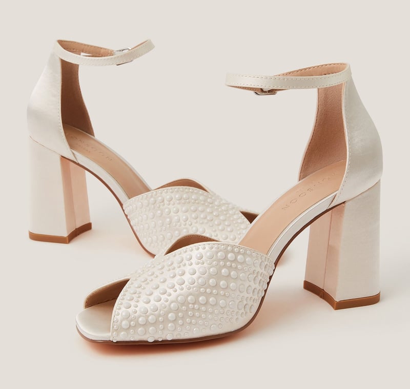 a pair of ivory coloured peeptoe wedding shoes with block heel adorned with pearl detail