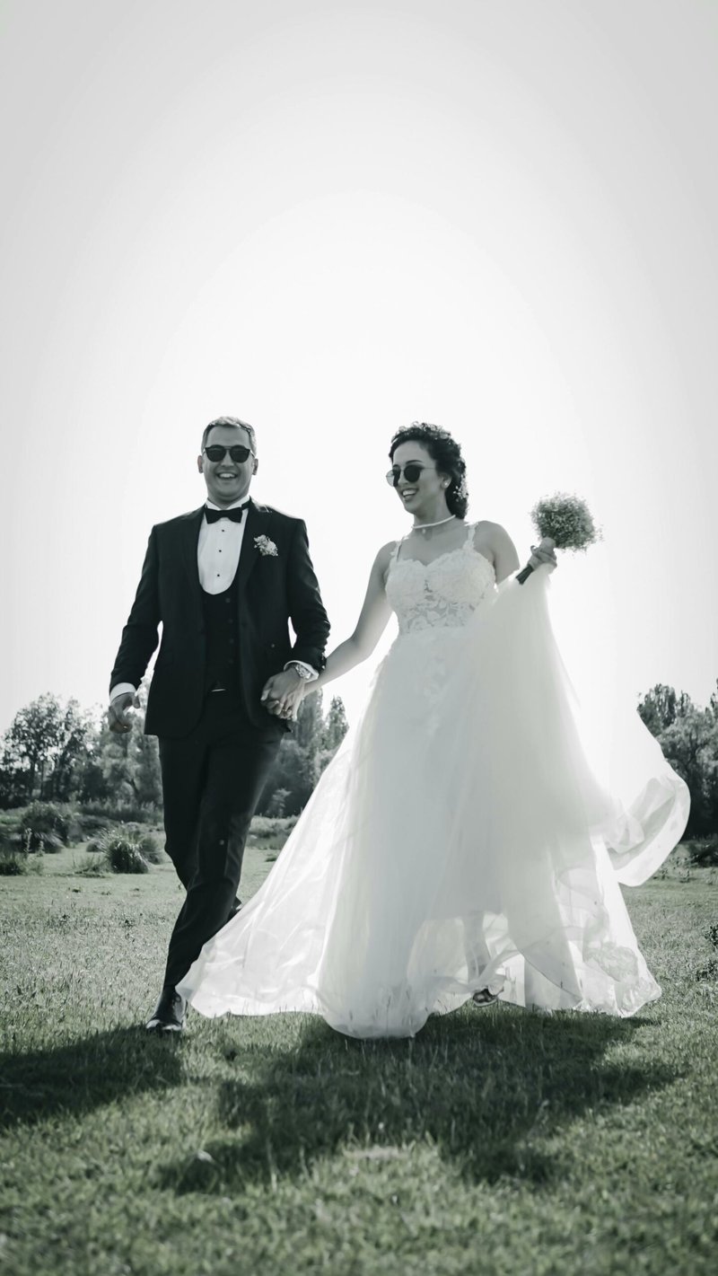 Bride and groom hand in hand in sunglasses at their New Zealand wedding