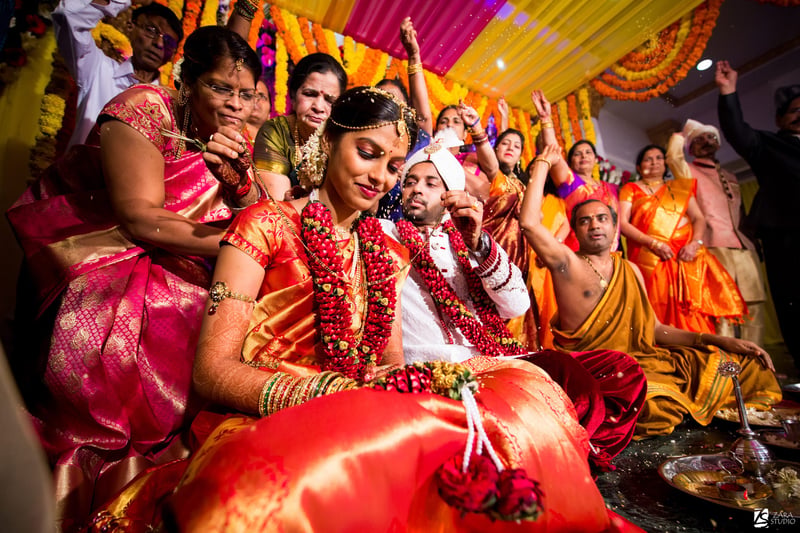 a hindu wedding showing the tying of the Mangalasutra around the bride's neck