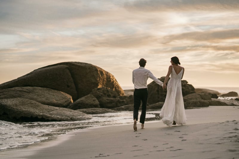 Bride and groom walking hand in hand along a new zealand beach