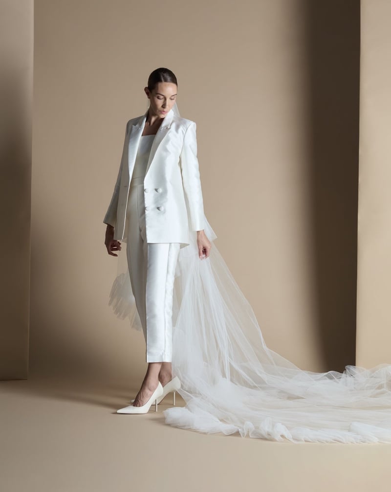 a model wears a tailored Mikado fabric bridal suit with corset top and cathedral-length veil. 