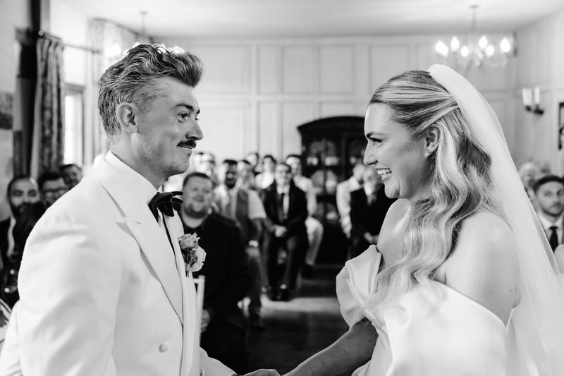 a bride and groom smile at each other during their civil ceremony