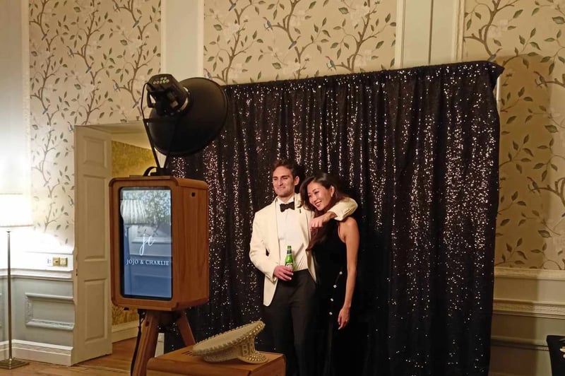 couple posing for a wedding photo booth in front of a sequin back drop 