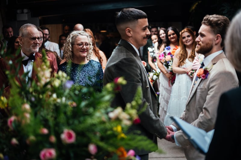 An LGBTQ couple look emotional as they say their wedding vows in a civil ceremony.