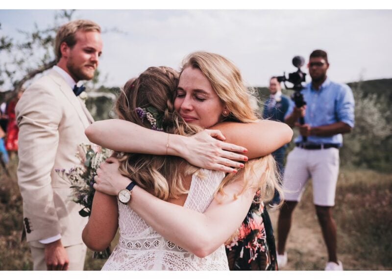 Emotionale Umarmung zwischen Braut und Freundin bei Sommerhochzeit