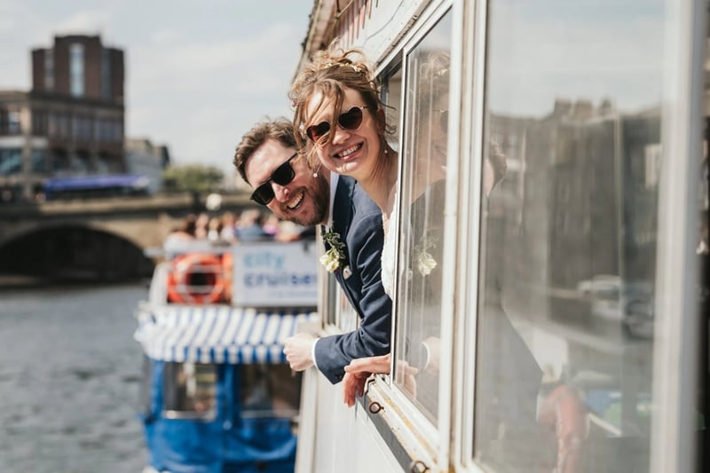Bride and groom peeking out of the window of a boat