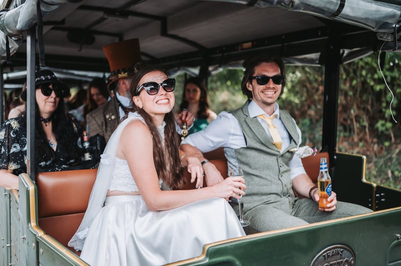 a bride and groom smile as they drink beer from a buggy at a vineyard wedding venue