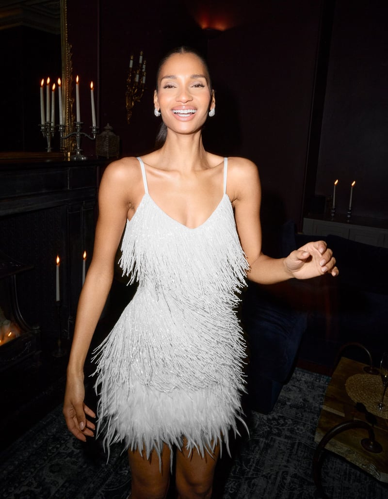 a bride smiling as she poses for the camera wearing a white beaded mini wedding dress