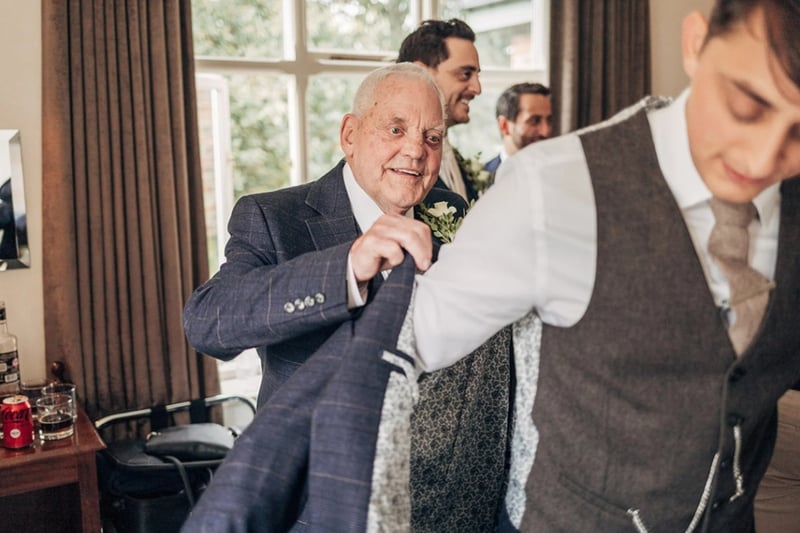 A father of the groom helping his son to put his suit jacket on