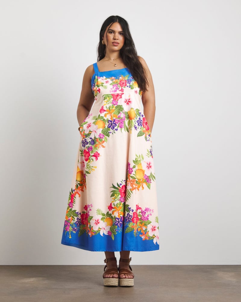 a plus size model wears a cotton strappy summer midi dress with colourful floral print.