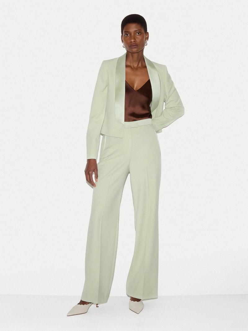 a model wears a pale green tuxedo suit with brown camisole underneath.
