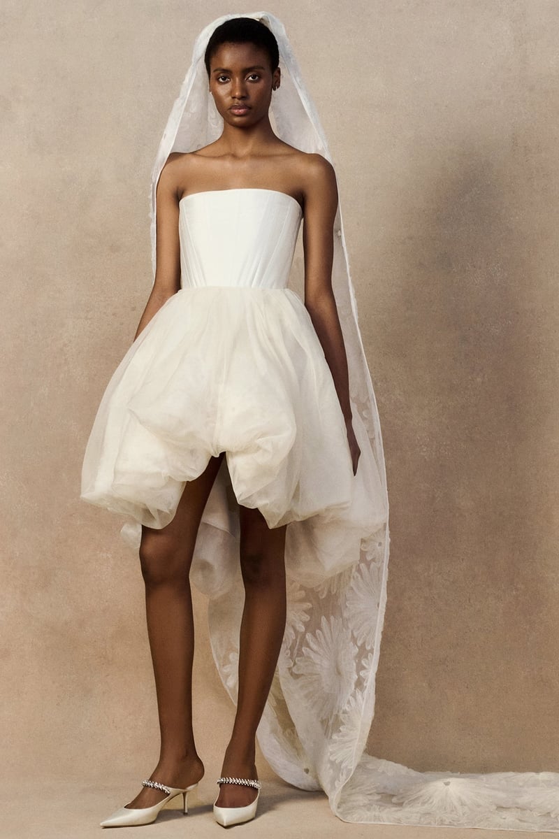 a model wears a short bubble-hem strapless wedding dress with dramatic cathedral-length veil.