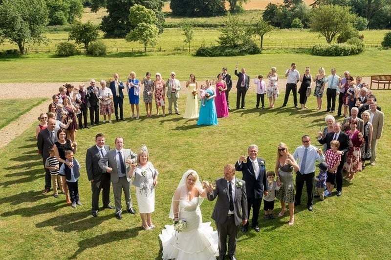 wedding guests standing in a heart on green grass