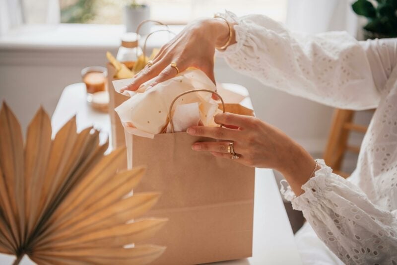 Person packt kleine Gastgeschenke in eine Papiertüte für eine Hochzeit