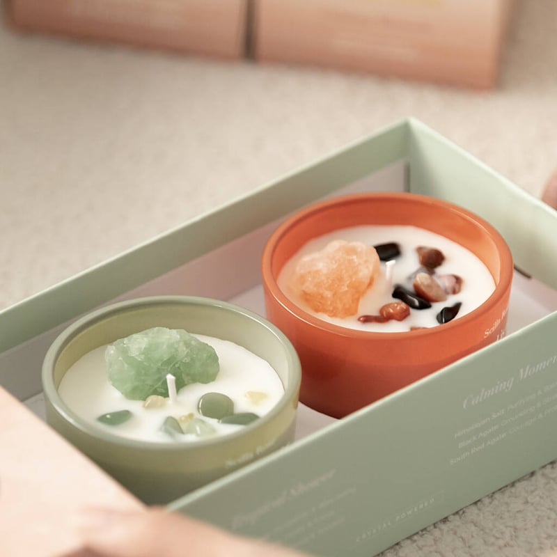 an orange and green candle filled with semi precious crystals and gemstones in a green gift box