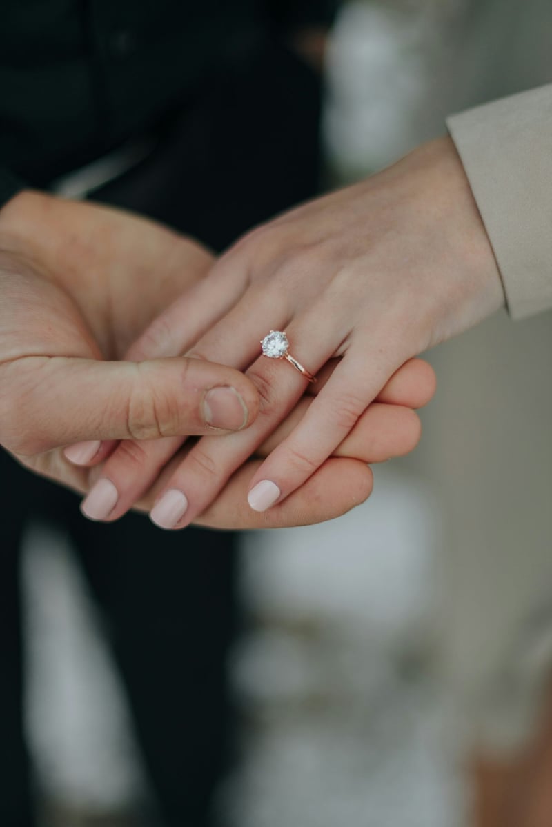 A man holding a woman's hand to show off her diamond engagement ring