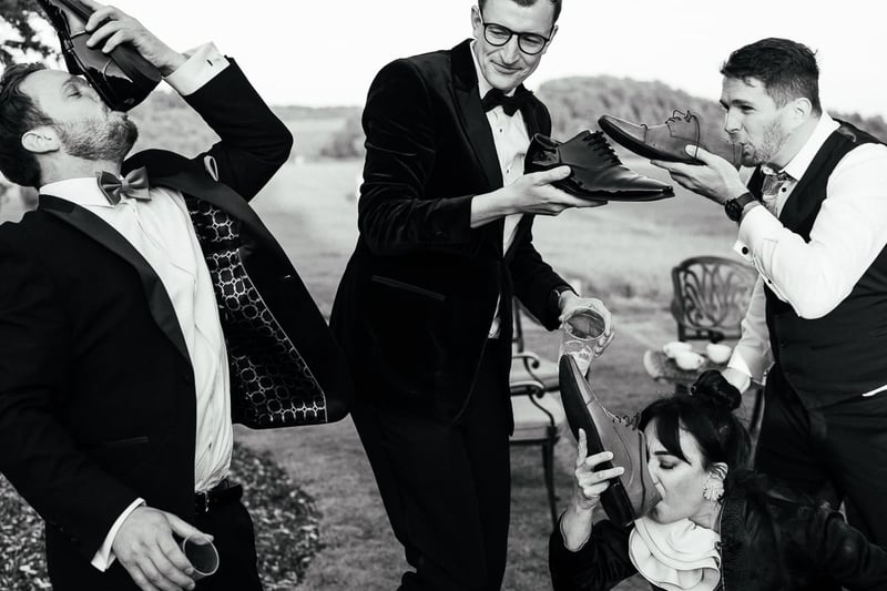 members of the wedding party joke around as they pretend to drink from their shoes.