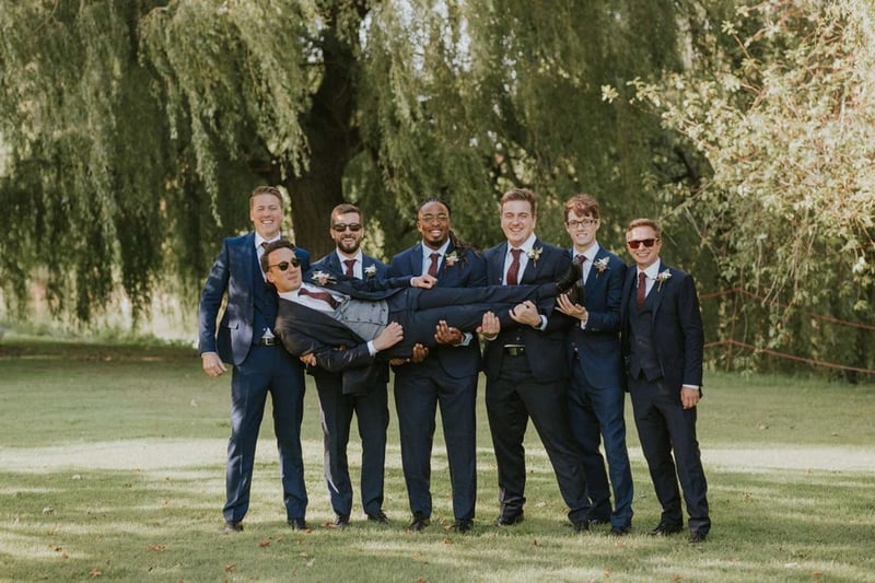 Groomsmen holding the groom who is lying horizontally in front of them