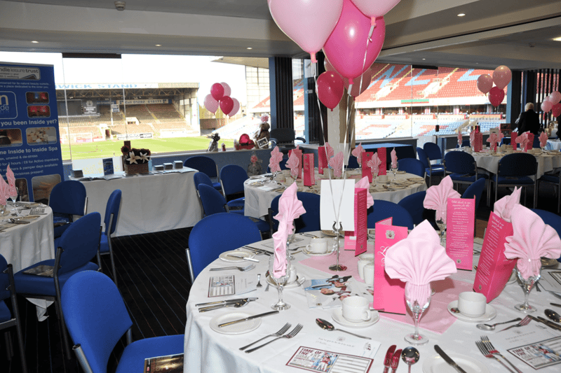A wedding reception room at Burnley Football Club's Turf Moor, with pink balloon decorations, overlooking the pitch