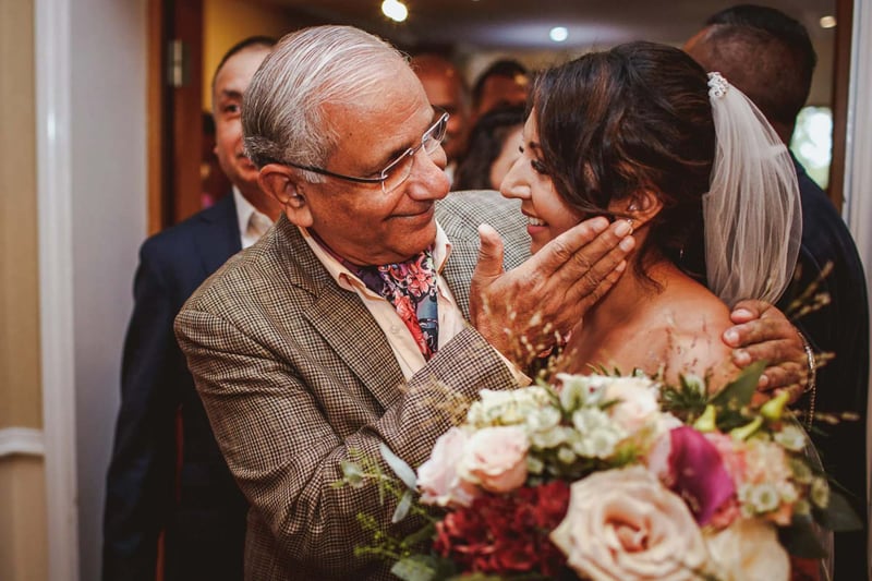 A proud father of the bride cupping his daughter's face