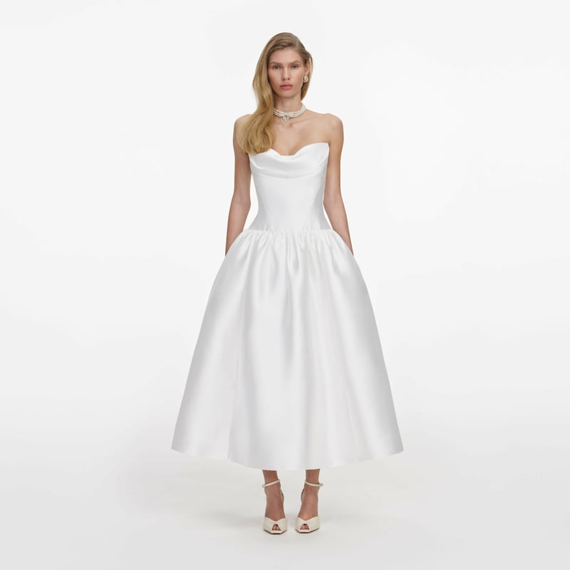 a model wears a strapless white taffeta midi dress with drop-waist bodice and A-line skirt.