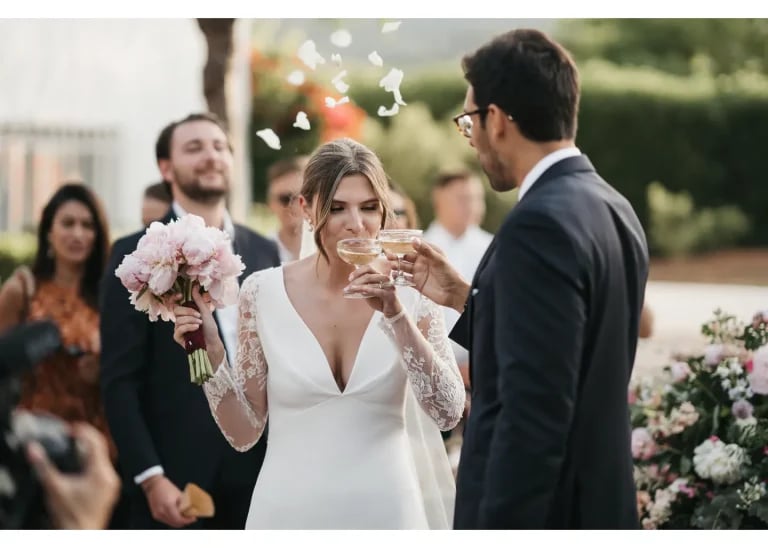 Braut und Bräutigam stoßen bei der Hochzeit an, mit rosa Brautstrauß