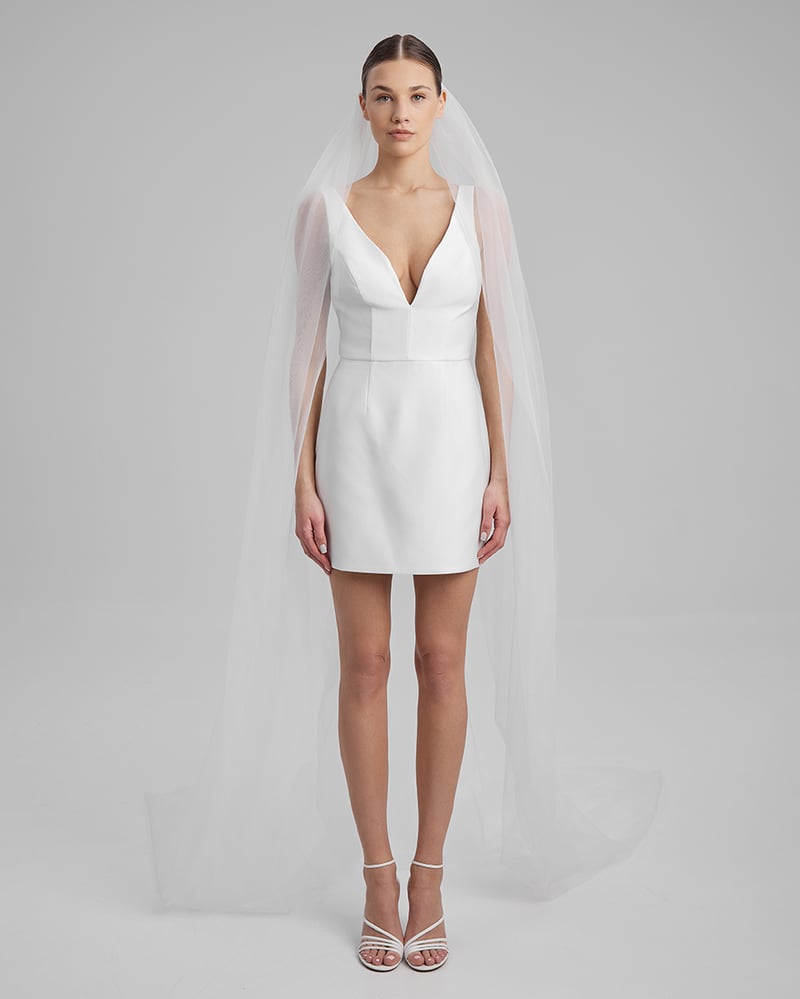 a model wears a short white wedding dress with v-neck and long veil