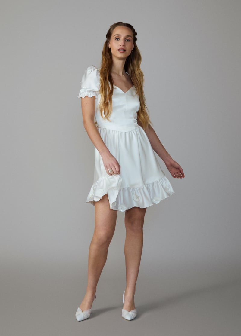 a model wears a short satin wedding dress with cap puff sleeves.