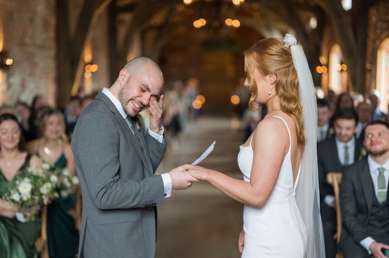 a tearful groom wipes his eyes as he reads his wedding vows at his ceremony.