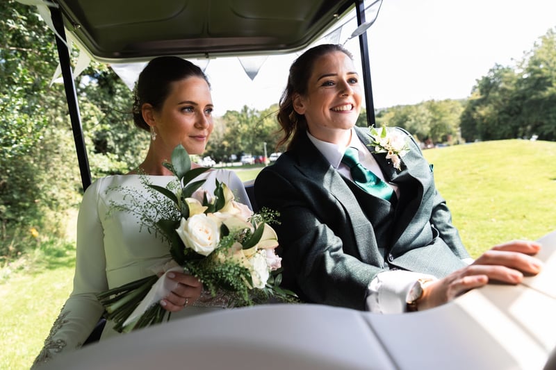 two brides making their way to their wedding reception in a golf buggy.