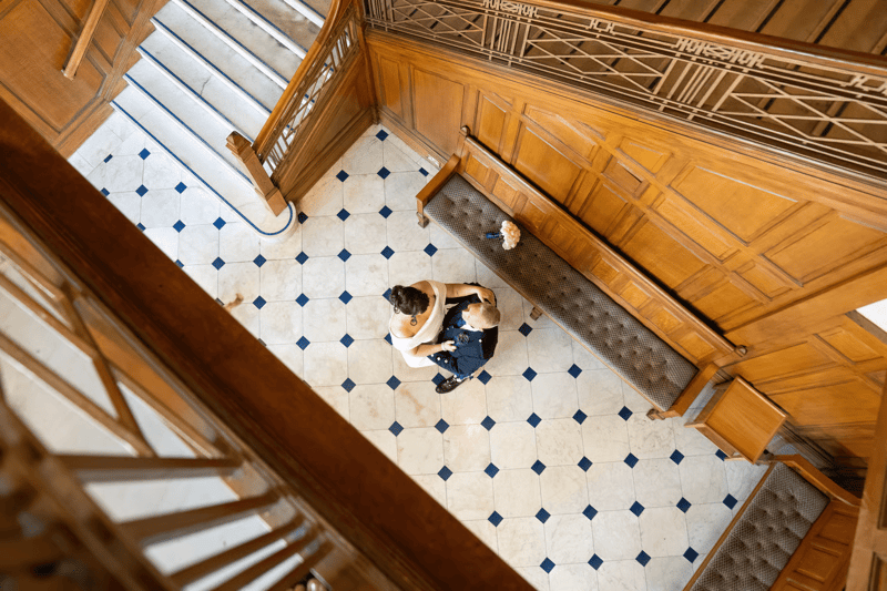 An aerial view looking down at a wedding couple on an ornate tiled staircase inside Ibrox Stadium, Glasgow
