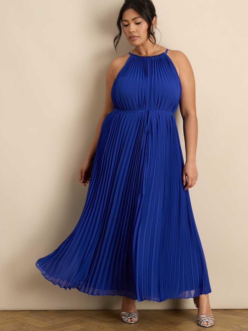 a curve model wears a deep blue pleated chiffon halterneck dress.