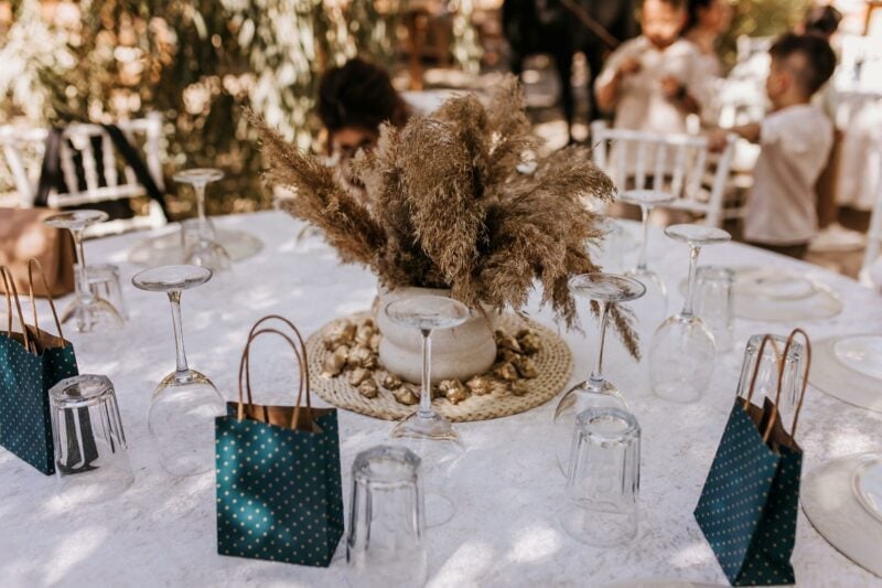 Dekorierter Hochzeitstisch im Freien mit Pampasgras, Gläsern und kleinen Gastgeschenken