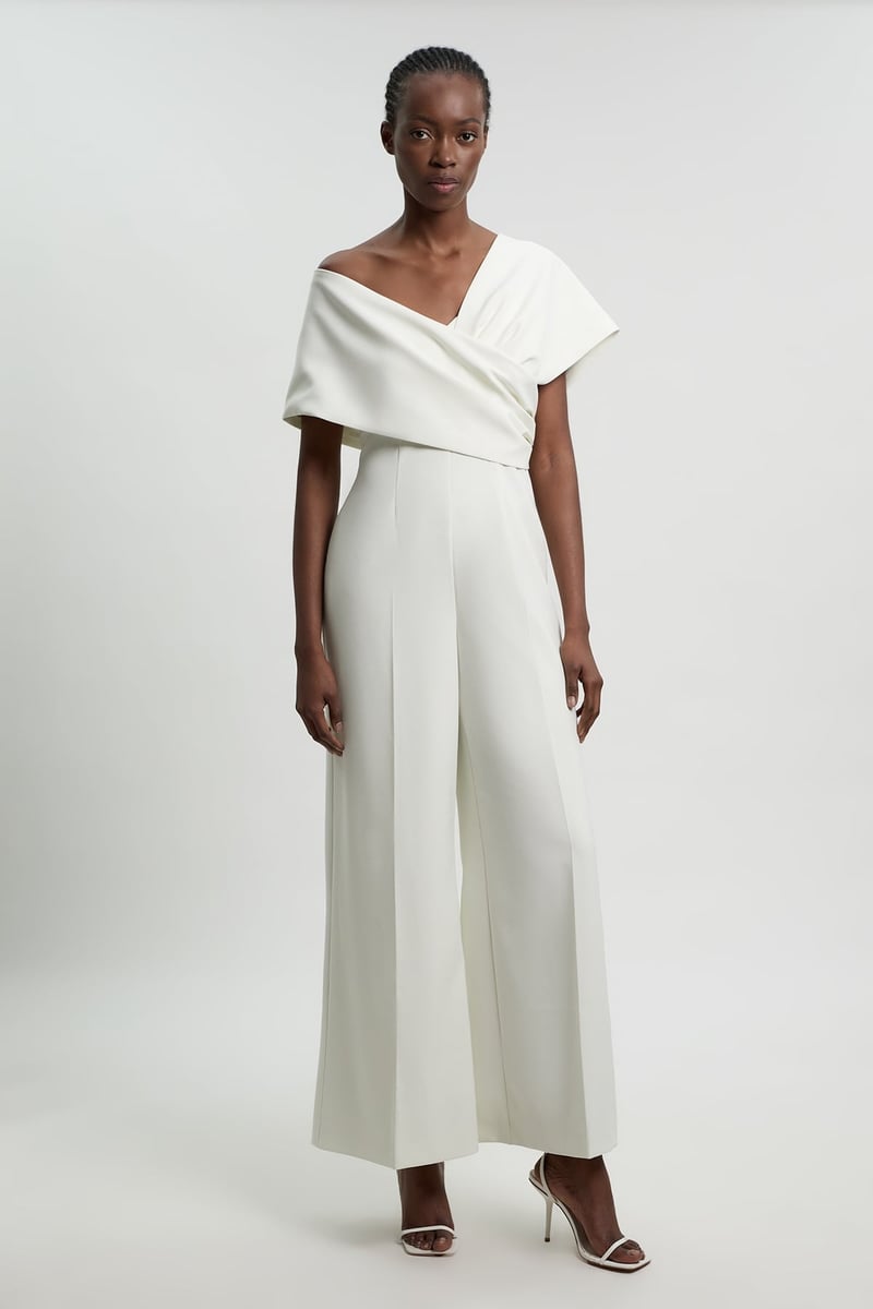 a model wears a stretch crepe jumpsuit with wide legs and off the shoulder asymmetric neckline.