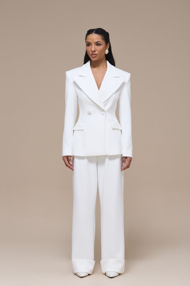 a model wears a white wedding suit featuring a structured double-breasted blazer with shoulder pads.