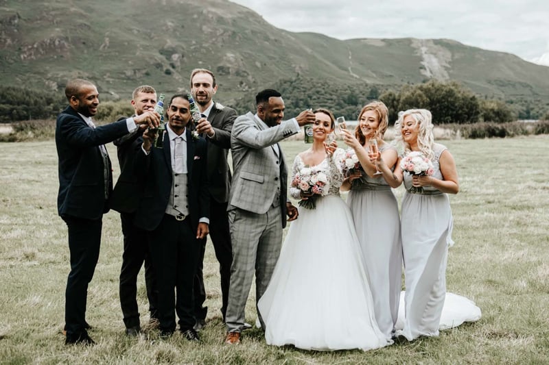 A wedding party toasting with drinks outdoors