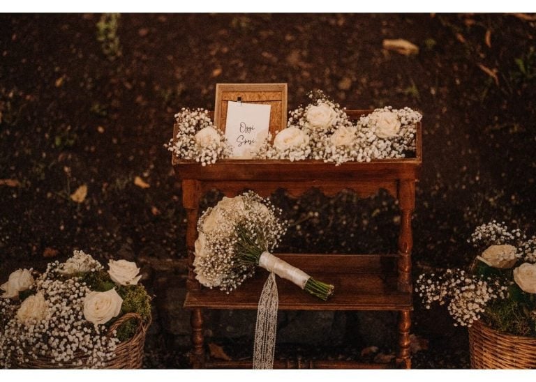 Rustikale Hochzeitsdekoration mit weißen Blumen und Brautstrauß auf Holztisch