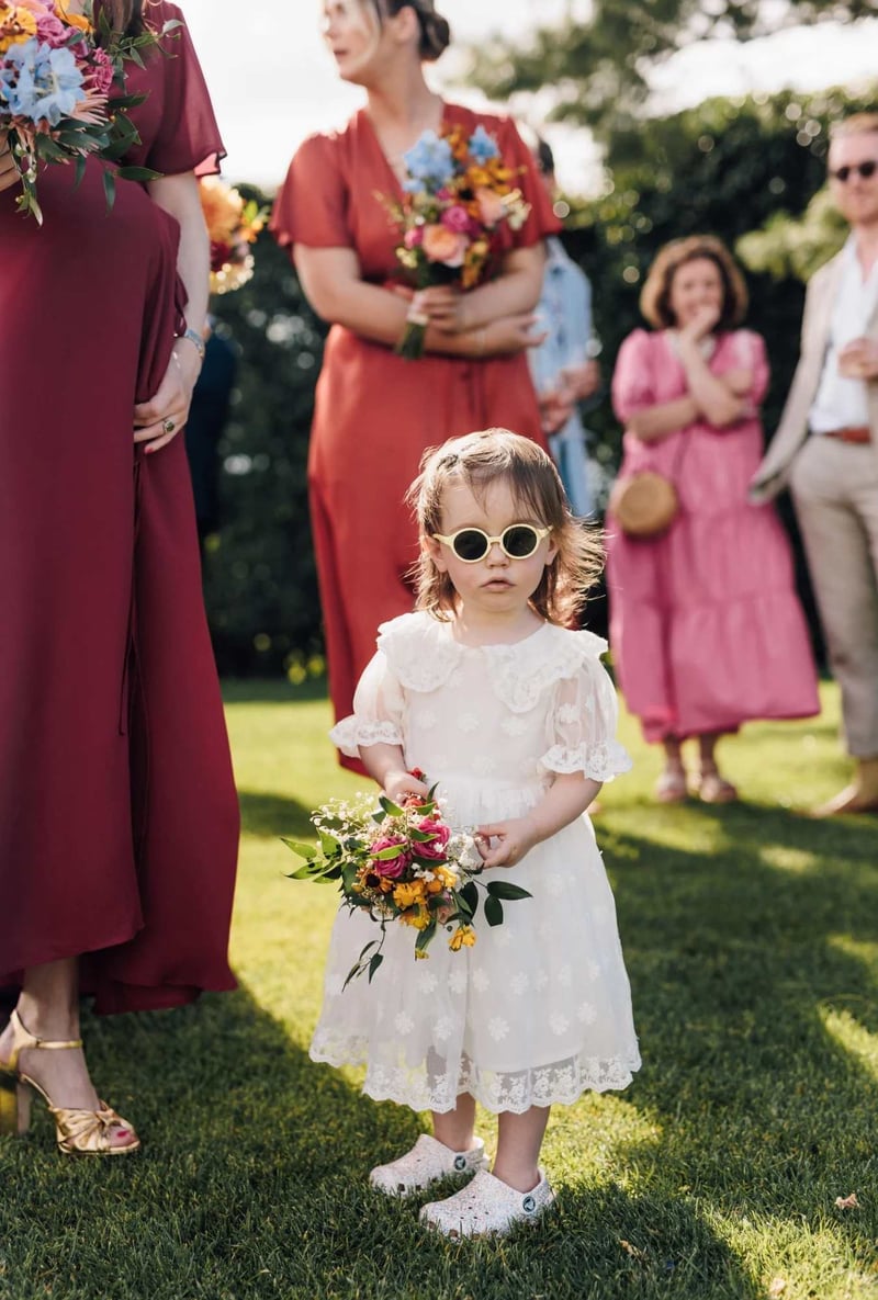 Flower girl wearing sunglasses and holding a small bouquet