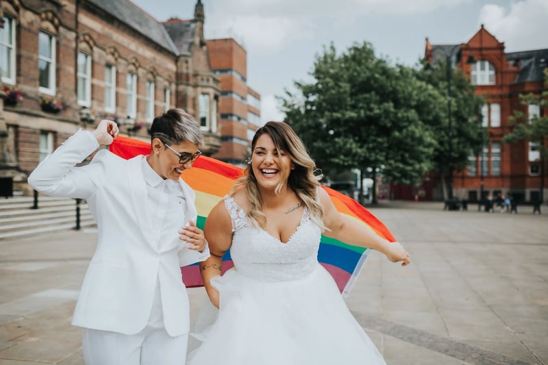 An lgbtq+ couple laughing and holding a rainbow flag