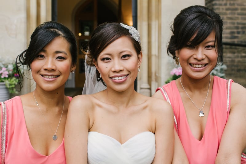 a bride and her two bridesmaids smile into the camera.