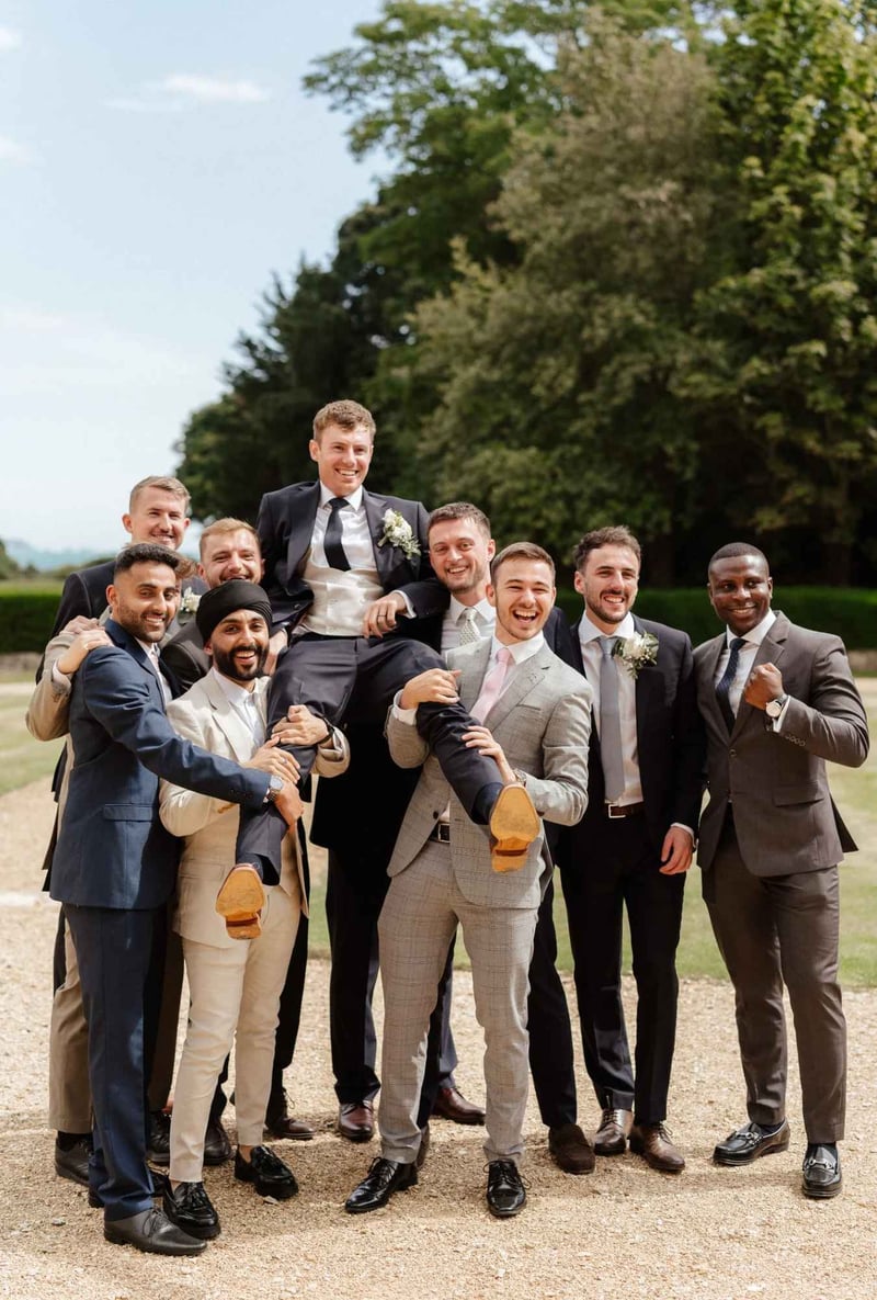 group of ushers holding the groom up in the air