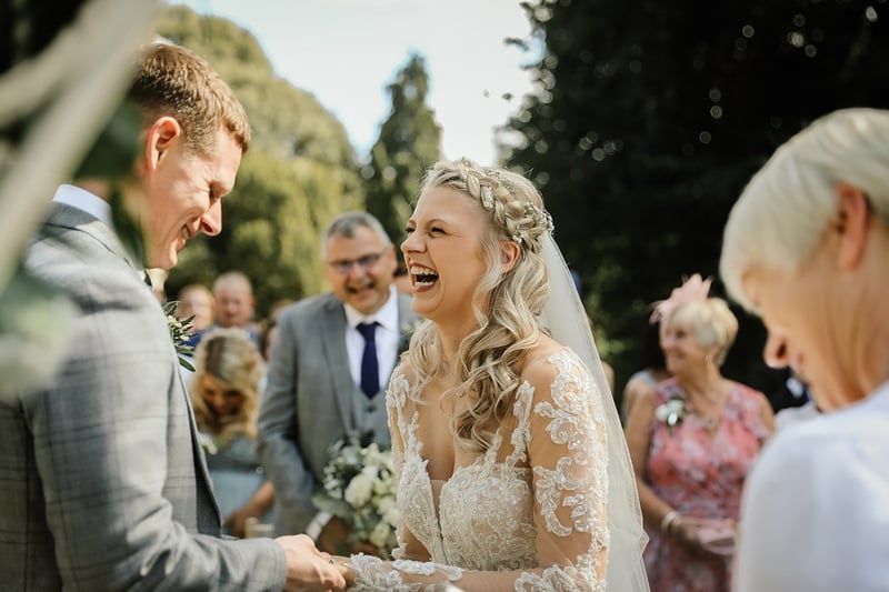 a bride laughs as she and her groom exchange vows at their outdoor wedding ceremony.