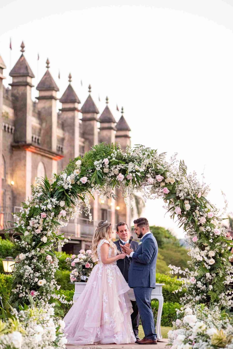 Wedding ceremony with a bride and groom at a fairytale wedding with a castle in the background and a floral arch