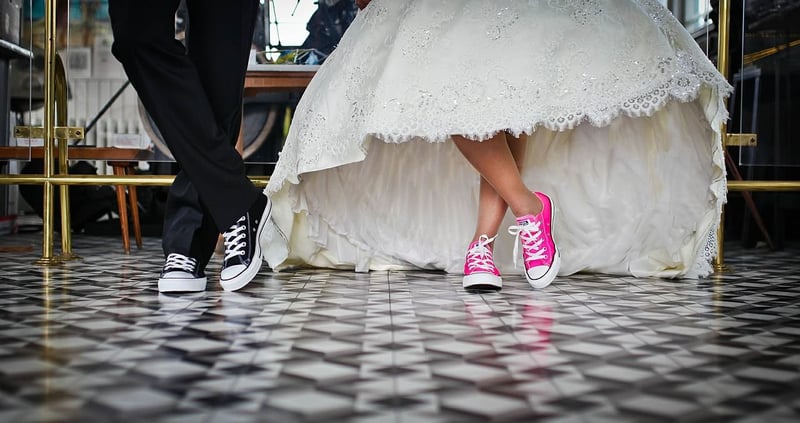 a close up of a bride and groom's black and pink Converse wedding shoes.