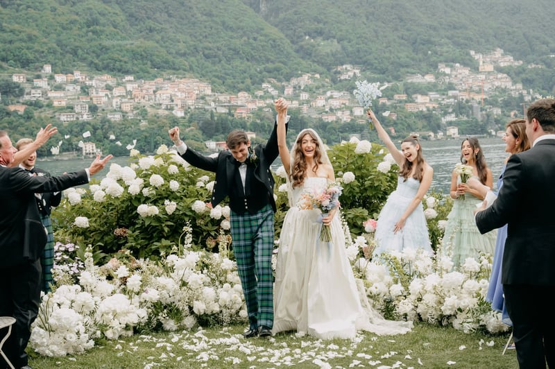 a bride and groom hold their hands in the air and smile at the end of their destination wedding ceremony.