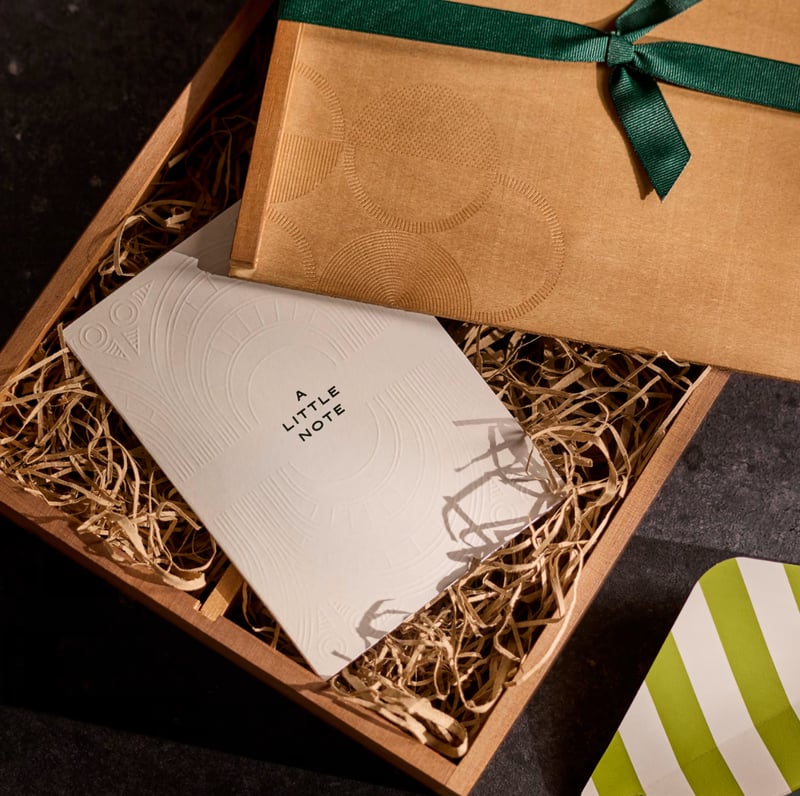 a wooden box with a little note inside containing a bottle of champagne in a green ribbon