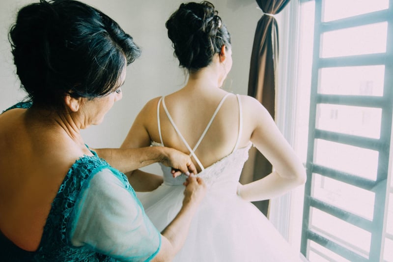 mother helping daughter get into wedding dress