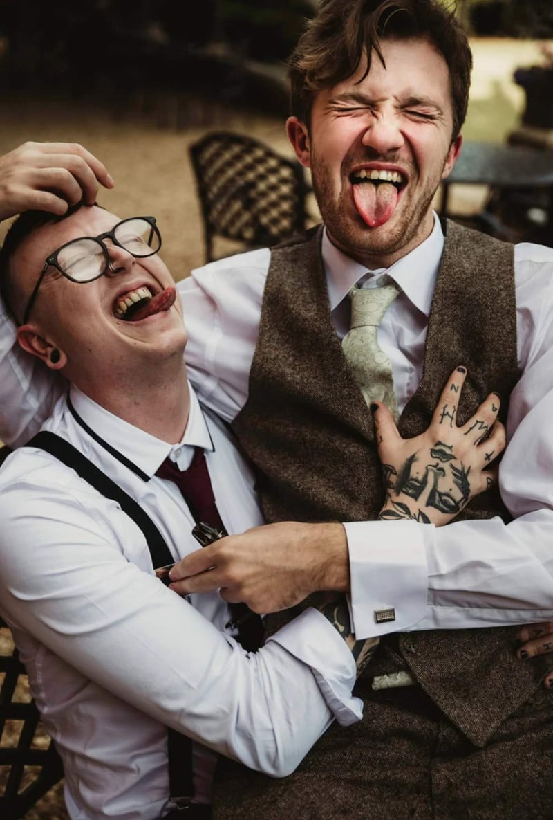 A best man and the groom clowning around and posing with their tongues out