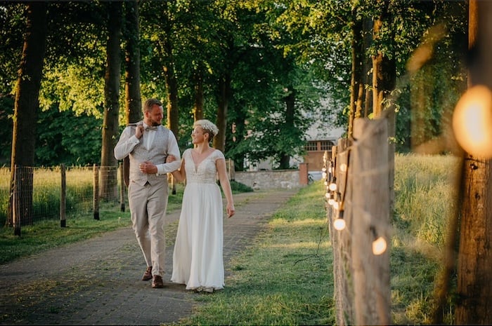 Hochzeitspaar auf einer Allee im Abendlicht